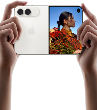iPhone Duo, Farbe Sternenweiß, in zwei Händen im Querformat gehalten, aufgefaltet, linke Seite mit 48 MP Dual Fusion Rückkameras, rechte Seite zeigt eine Person, die fotografiert wird, auf dem äußeren Display kann die fotografierte Person während der Aufnahme mit Duo Preview ihr Gesicht sehen